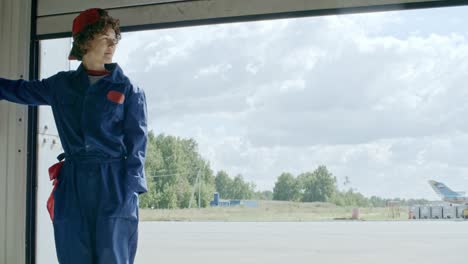 técnica mujer abriendo la puerta en el hangar de aviones