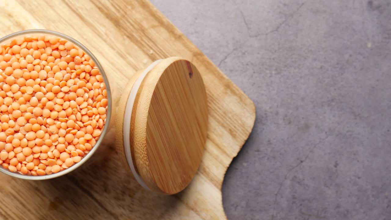 lentejas rojas en un cuenco de vidrio con tapa de madera