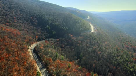 Drohnenaufnahmen-Einer-Malerischen-Bergautobahn-Mit-Wäldern-Und-Dem-Tal-Und-Ackerland-Darunter-Und-Bergen-Im-Hintergrund-Im-Herbst