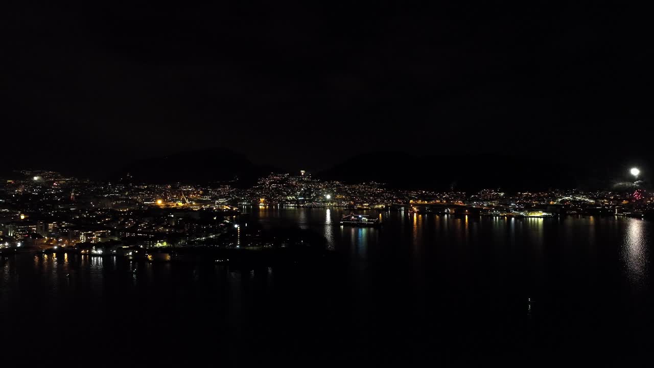 корабль покидает порт бергена во время фейерверка по всему городу во время празднования нового года - панорамный ночной аэроснимок - норвегия