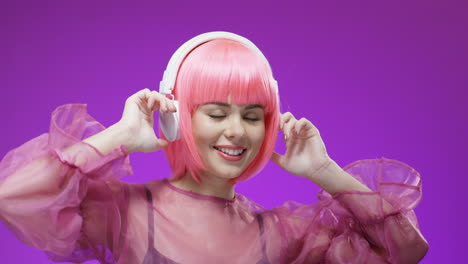 portrait of beautiful woman wearing a pink wig and headphones, dancing and laughing to the camera 1