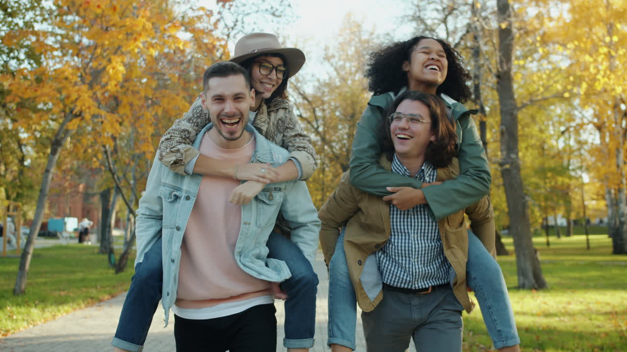 Friends having fun on a piggyback ride in an autumn park