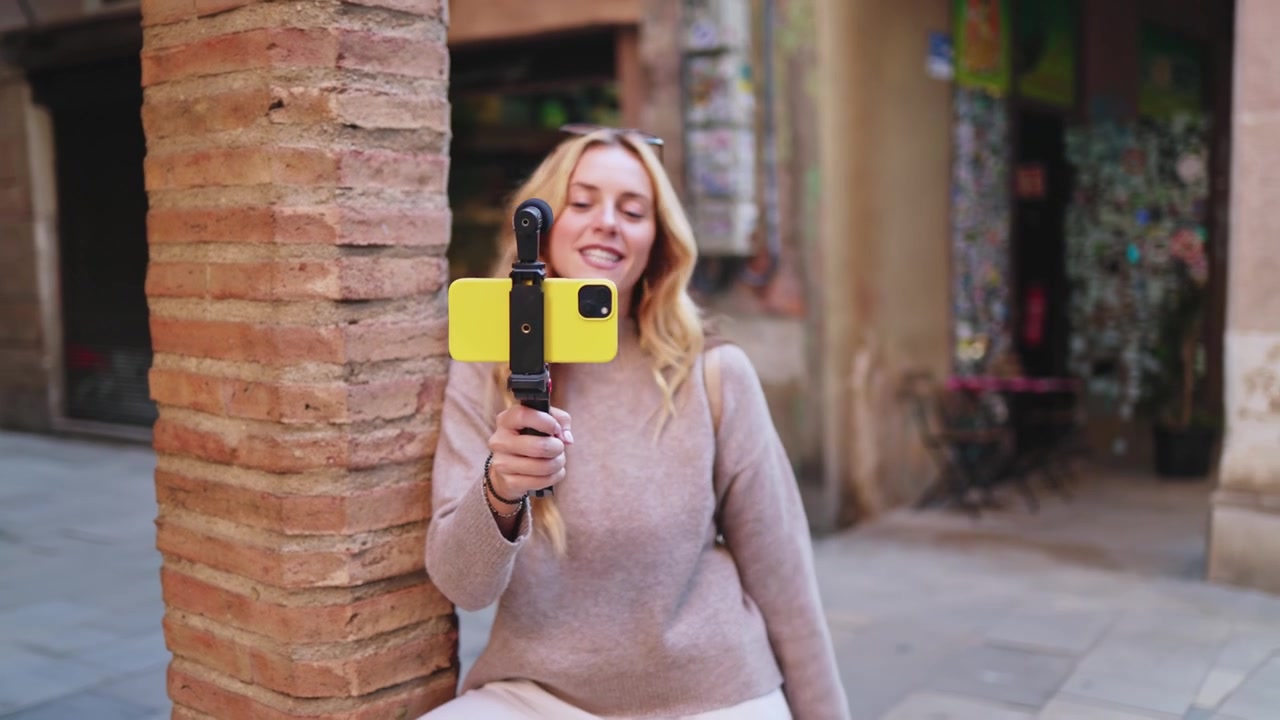 Donna bionda felice che fa vlogging per strada in città con lo smartphone
