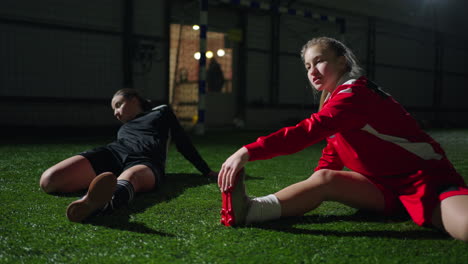 two female soccer players stretching before a game