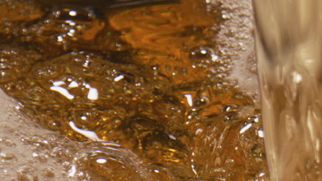 lager beer swirling goblet closeup. sparkling liquid moving inside glass vessel