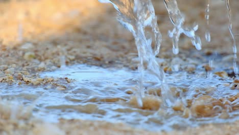 lots of water pouring out of a water container in the middle of dry desert land