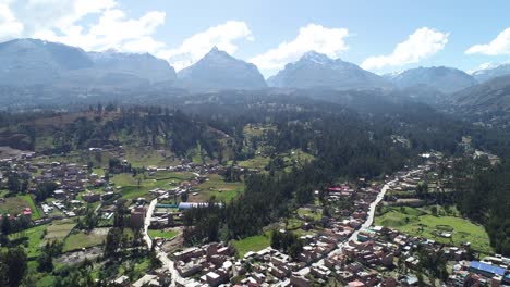 scenic aerial view of a rural andean town surrounded by lush green fields and towering snow-capped mountains. ideal for travel documentaries, tourism content, and nature photography.
