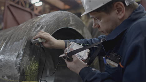 industrial worker inspecting metal pipe