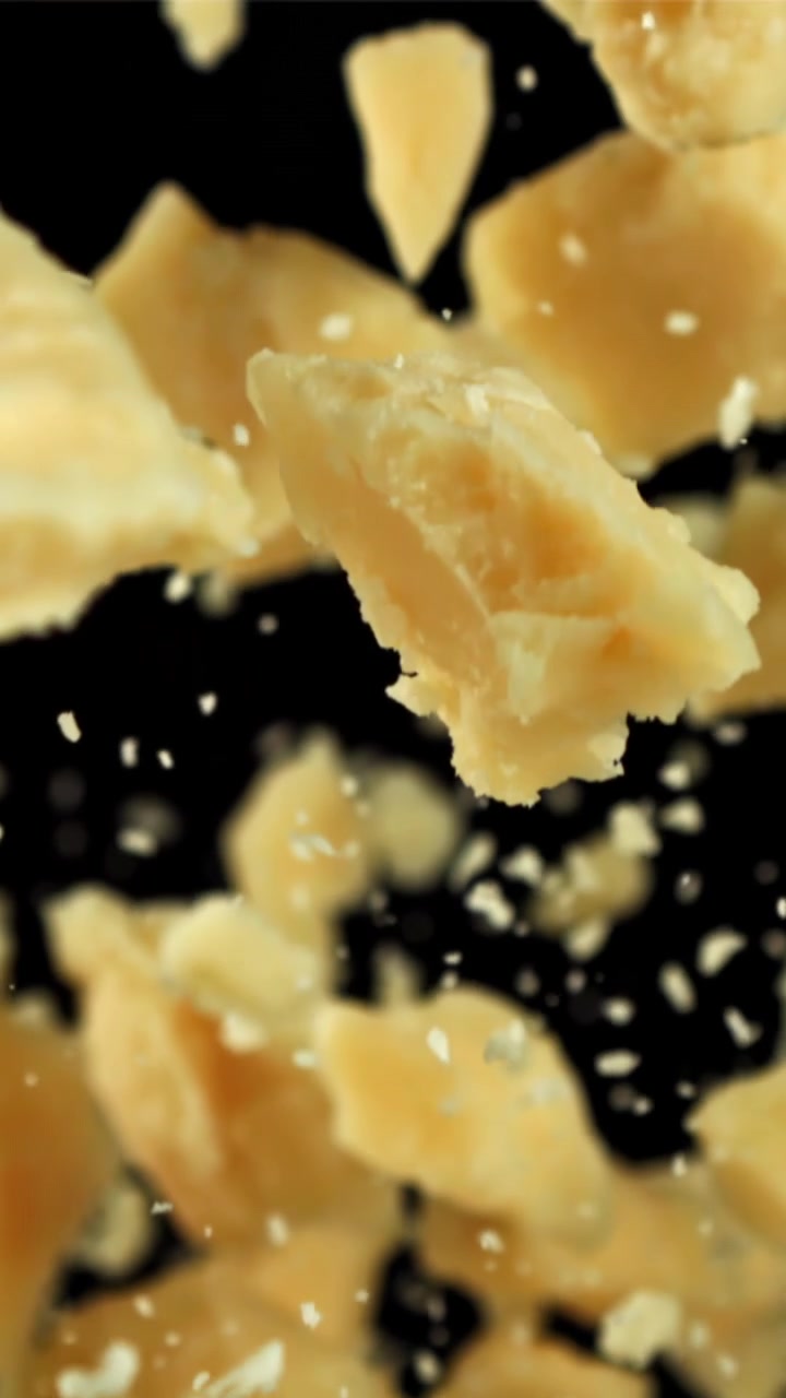 Pezzi di Parmigiano in caduta al rallentatore su sfondo nero