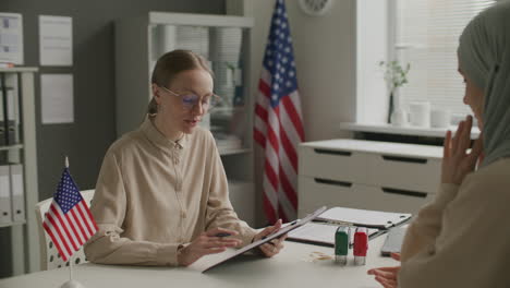 Female Visa Officer Discussing Application Form with Woman in Hijab