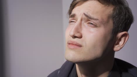 un joven guapo deprimido llorando.