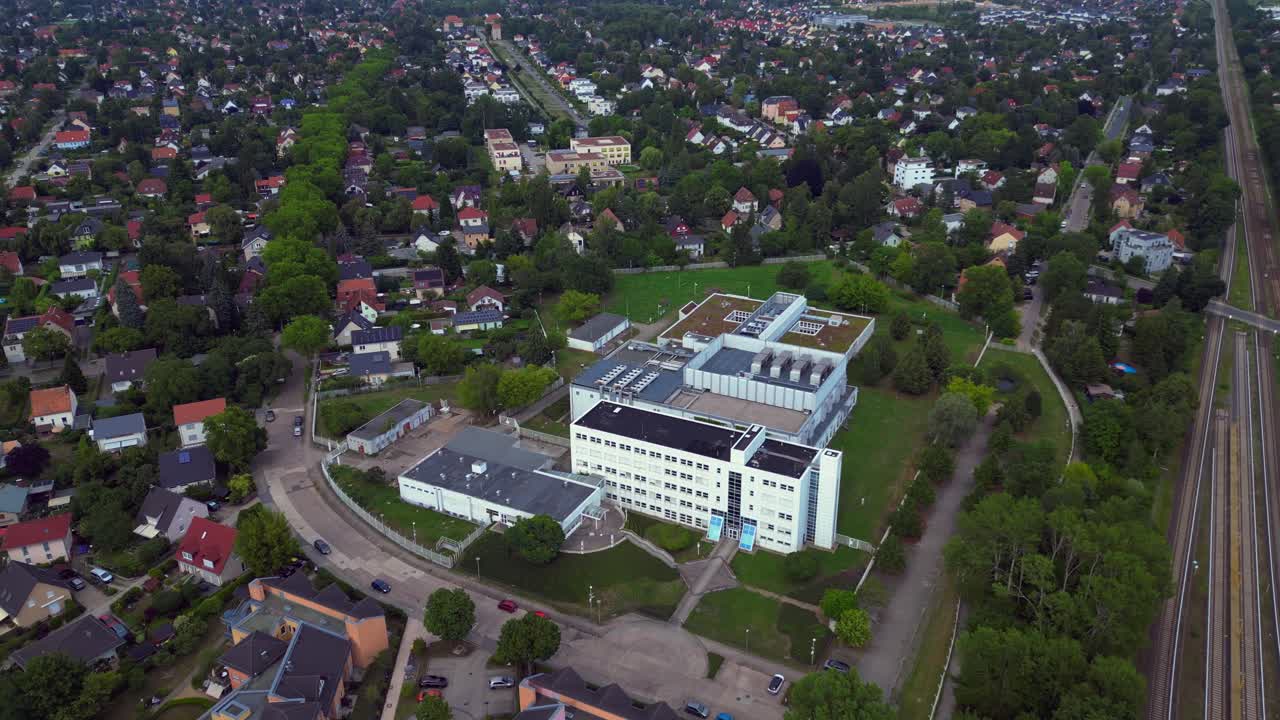 datacenter building with cooling system on the roof, surrounded by residential houses, showcasing urban and industrial integration. Lovely aerial view flight fly push forward drone