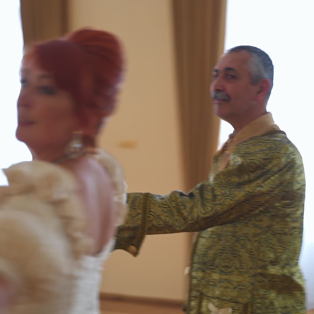 Aging couple in historic outfits performing a dance. Adult people in a big dance ballroom of a castle