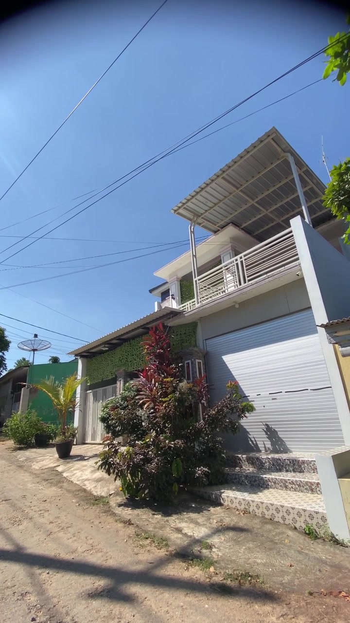 Casa moderna de dos pisos con balcón y garaje en un día soleado.