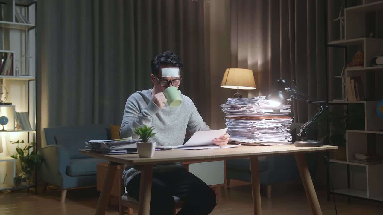 Sick Asian Man Drinking Water While Working Hard With Documents At The Home