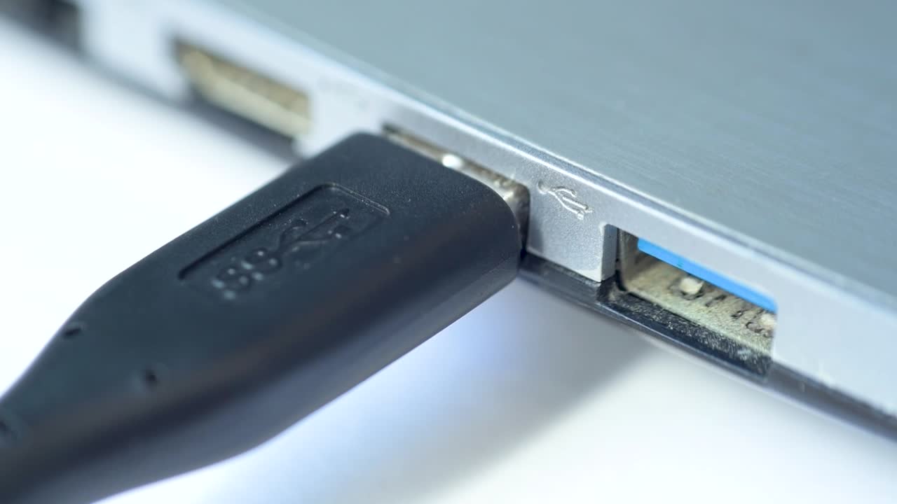 Fingers connecting a usb cable to a laptop port. Macro.