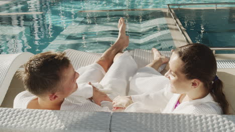 couple relaxing by the pool in bathrobes