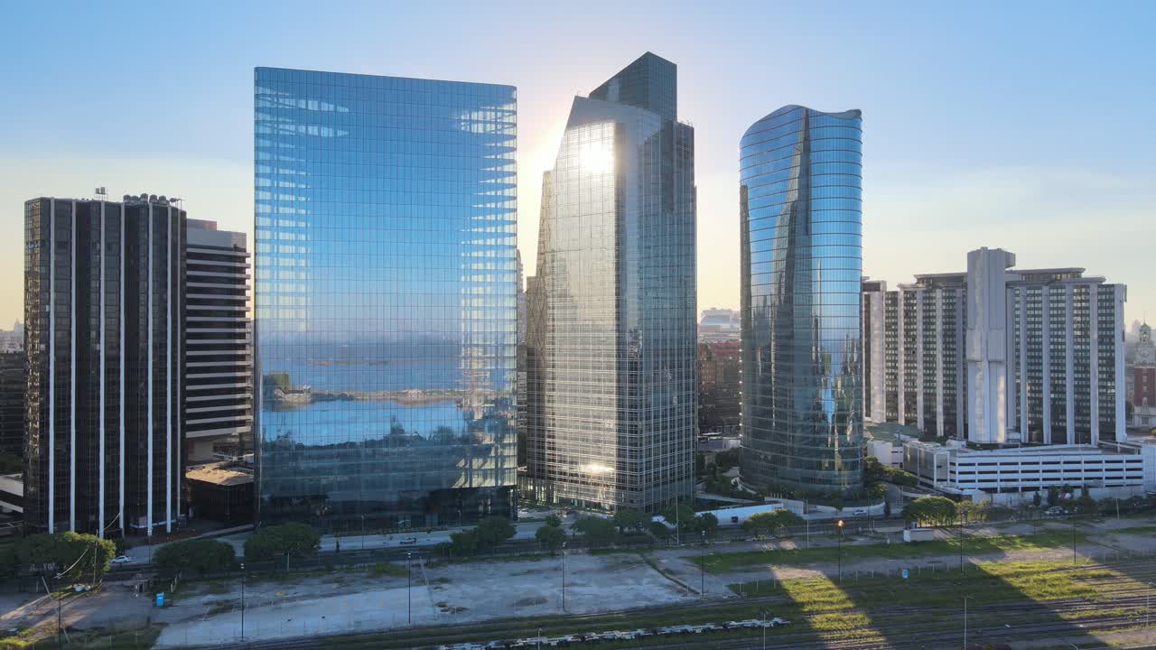 Aerial pan right of window glass skyscrapers mirroring Puerto Madero neighborhood at sunset, Buenos Aires
