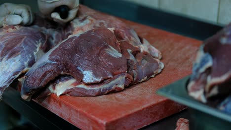 el chef corta carne cruda con un cuchillo de cerca.