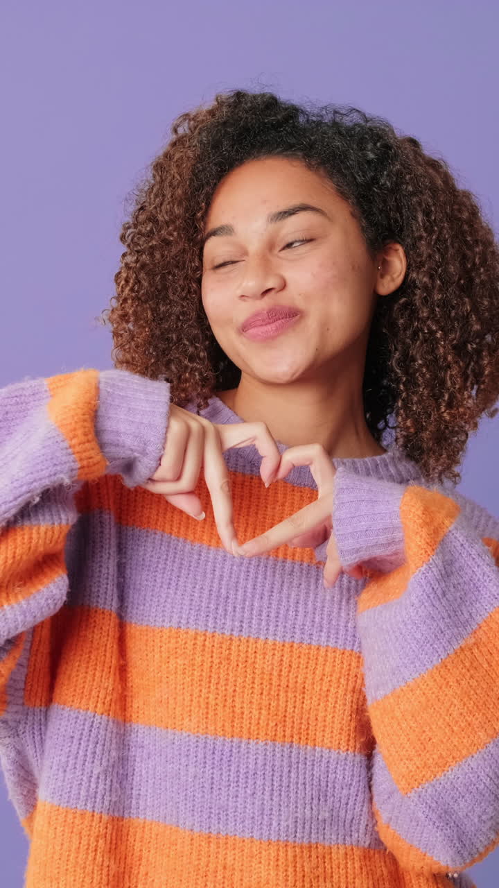 Giovane donna felice che fa un gesto a cuore con le mani