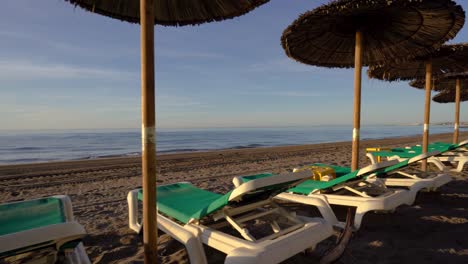 interesting gimbal stabilized shot of marbella beach with sunbeds and parasols, dynamic 4k smooth moving footage of costa del sol coastline at sunrise