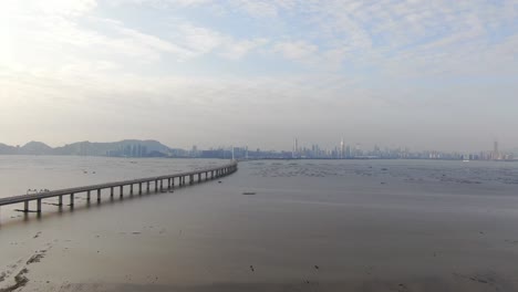 hong kong shenzhen bay bridge with tin shui wai buildings in the horizon and fish and oyster cultivation pools, aerial view