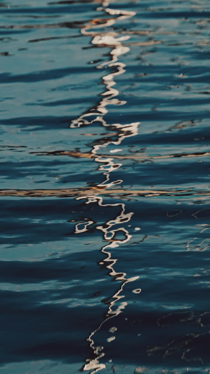 Riflessi della città sulle onde del mare. Verticale