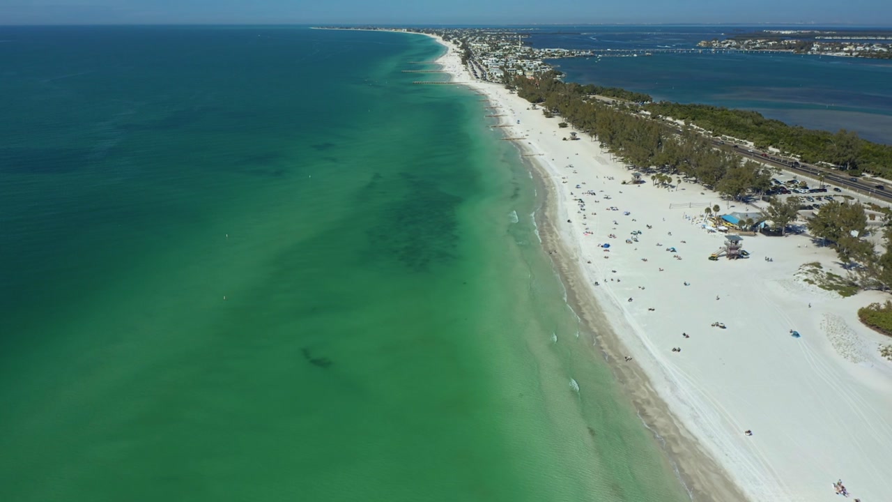 A serene stretch of white sandy beach meets calm, clear waters along the Gulf Coast. Perfect for travel ads, nature documentaries, and coastal lifestyle promotions.