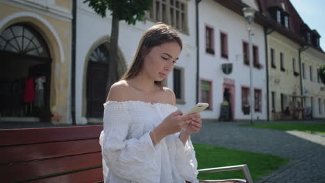 young woman texting on smartphone in european city