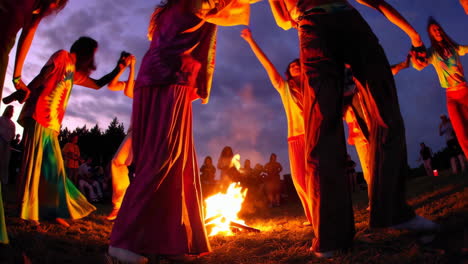 people dancing around a bonfire at sunset