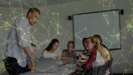 Animation-of-shapes-over-caucasian-male-teacher-with-laptop-and-diverse-schoolchildren