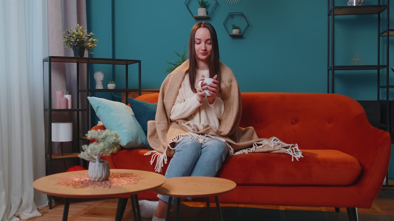 따뜻한 색 스웨터를 입은 미소 짓는 젊은 성인 여성의 초상화 가정에서 휴식을 취하는 뜨거운 음료 컵
