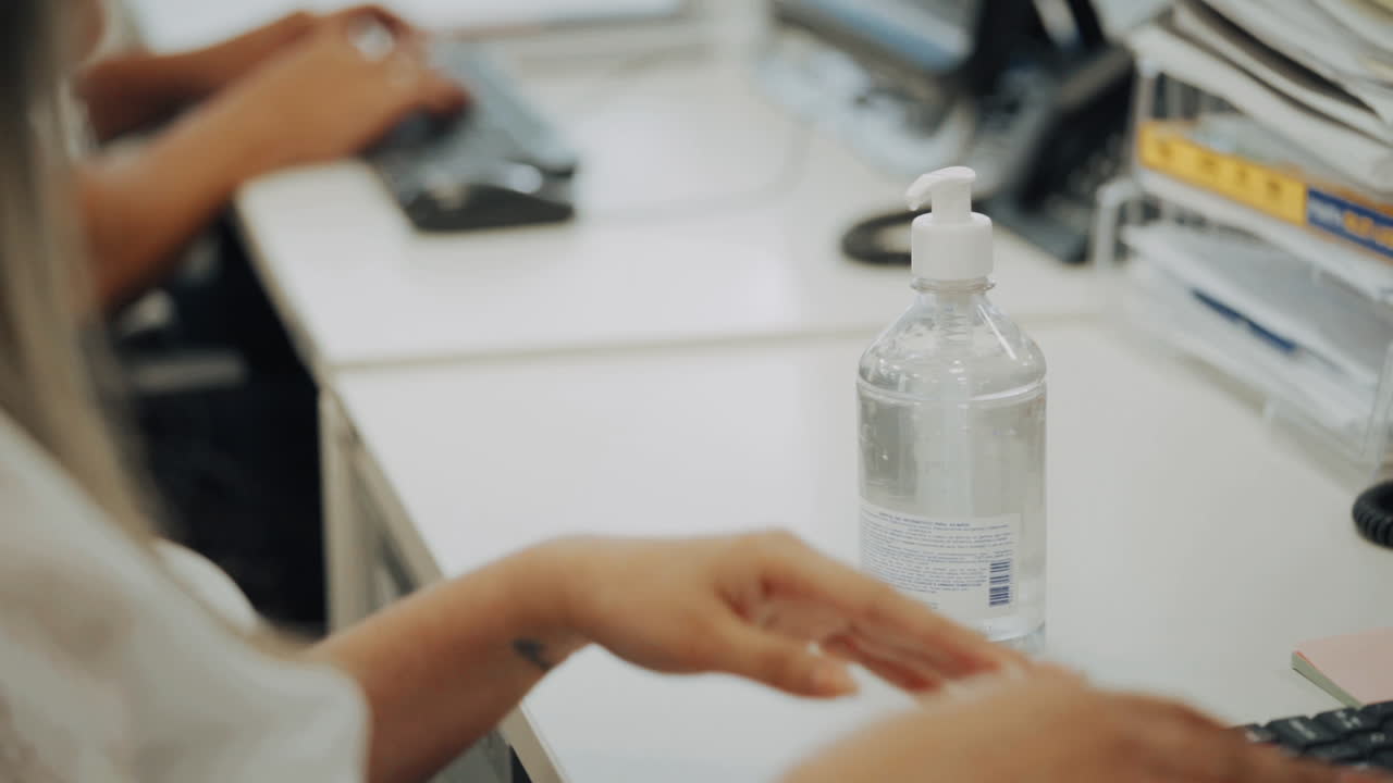 Detail of a woman mother in the office washing her hands with alcohol gel as a preventive measure