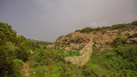 vista de drones de las líneas victoria en malta en un hermoso día despejado mientras un par de turistas caminan por el camino