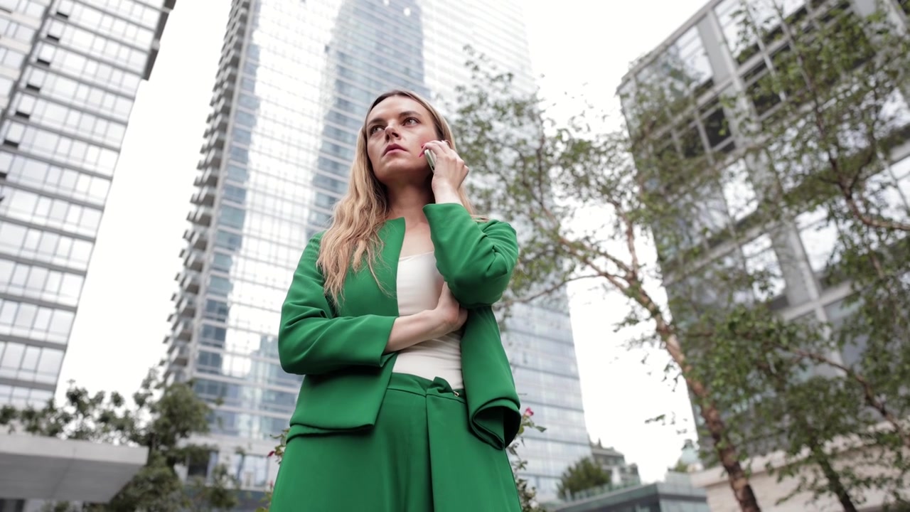 Mujer de negocios usando un teléfono inteligente frente a un edificio de oficinas moderno