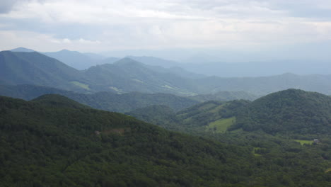 Drone-Landscape-Reveal-Shot-of-Woman-Standing-on-Rock-Looking-at-Mountain-Horizon-on-Cloudy-Overcast-Day-in-Tennessee