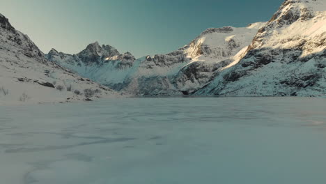 drone shot of a frozen lake in lofoten with mountains in the background