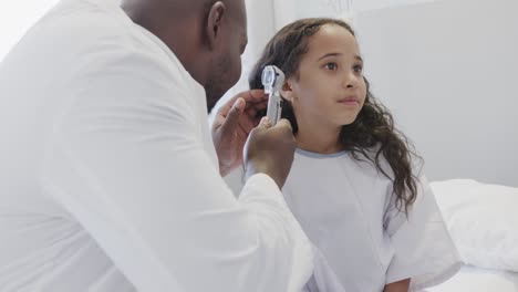 feliz médico diverso examinando paciente niña enferma con otoscopia en el hospital en cámara lenta