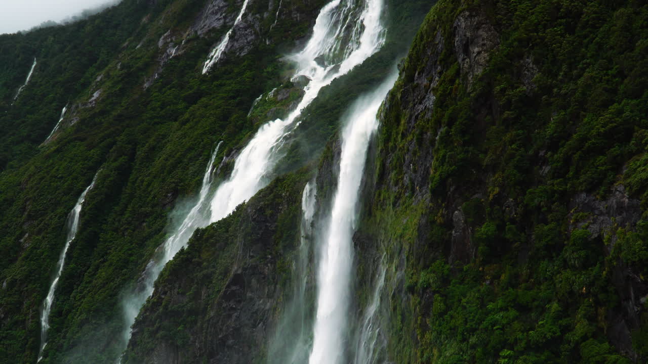 inclínate hacia arriba para revelar las altas cascadas de milford sound en moody cloudy weather, nueva zelanda