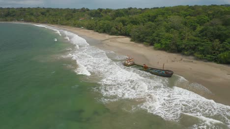 Shipwreck-on-tropical-coastline-of-Costa-Rica-with-big-swell-waves,-aerial