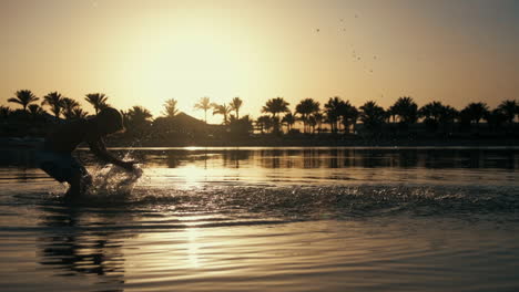 active young man walking at resort beach. happy boy splashing water in sea.
