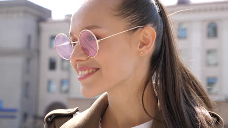 woman smiling outdoors in city with sunglasses