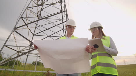 a group of engineers at a high-voltage power plant with a tablet and drawings walk and discuss a plan for the supply of electricity to the city. transportation of renewable clean energy.