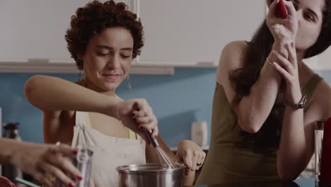 two women cooking together in a kitchen, consulting a smartphone