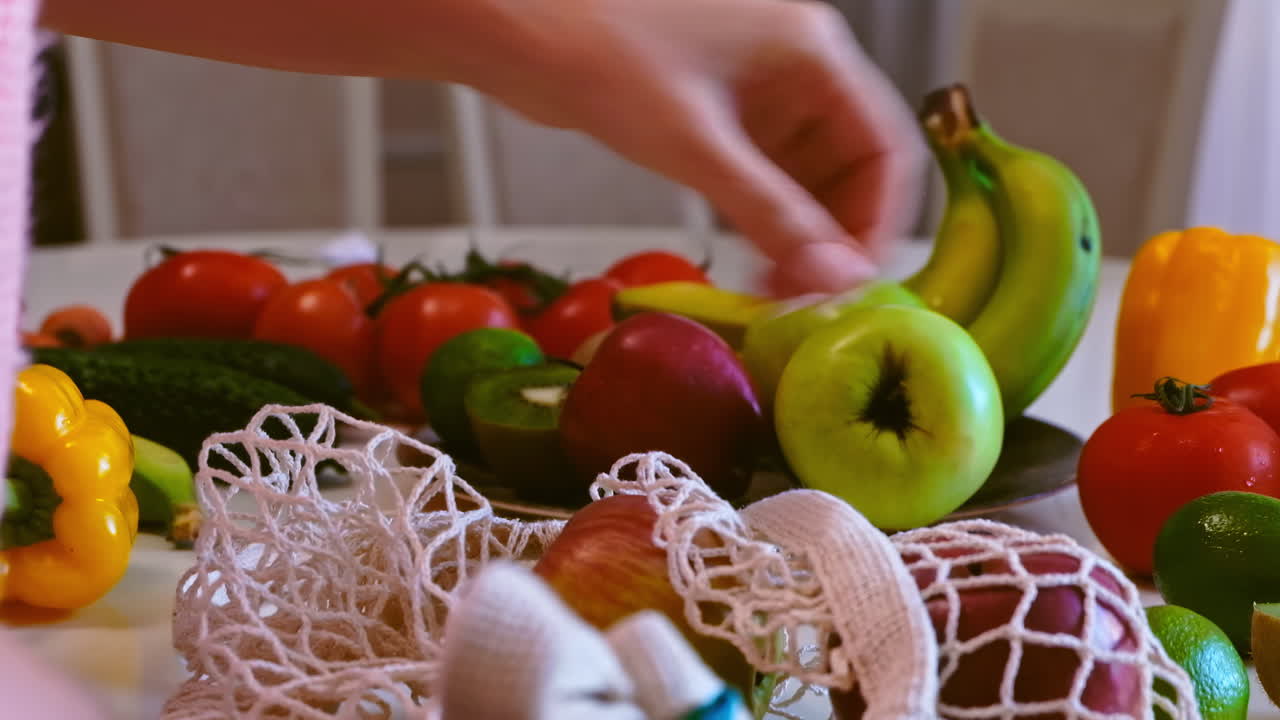 Woman's hands puts a grocery knitted eco bag with apples on the table and arranges them in a plate