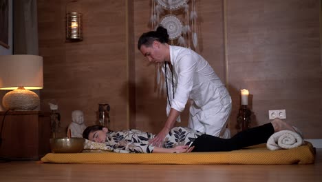 spiritual therapist massaging back of relaxed woman