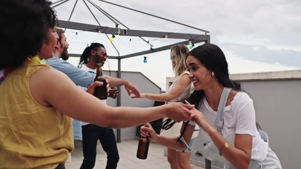 Friends celebrating with beer and dancing at a rooftop party