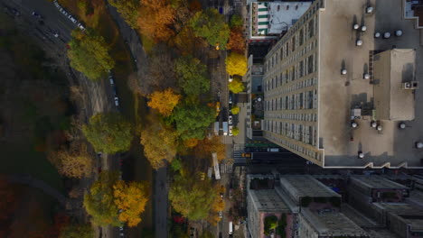 Aerial-birds-eye-overhead-top-down-view-of-street-between-urban-development-and-park-with-autumn-colour-trees.-Manhattan,-New-York-City,-USA