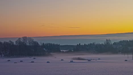 time-lapse of the vanishing mist at the orange rising sun over a winter landscape