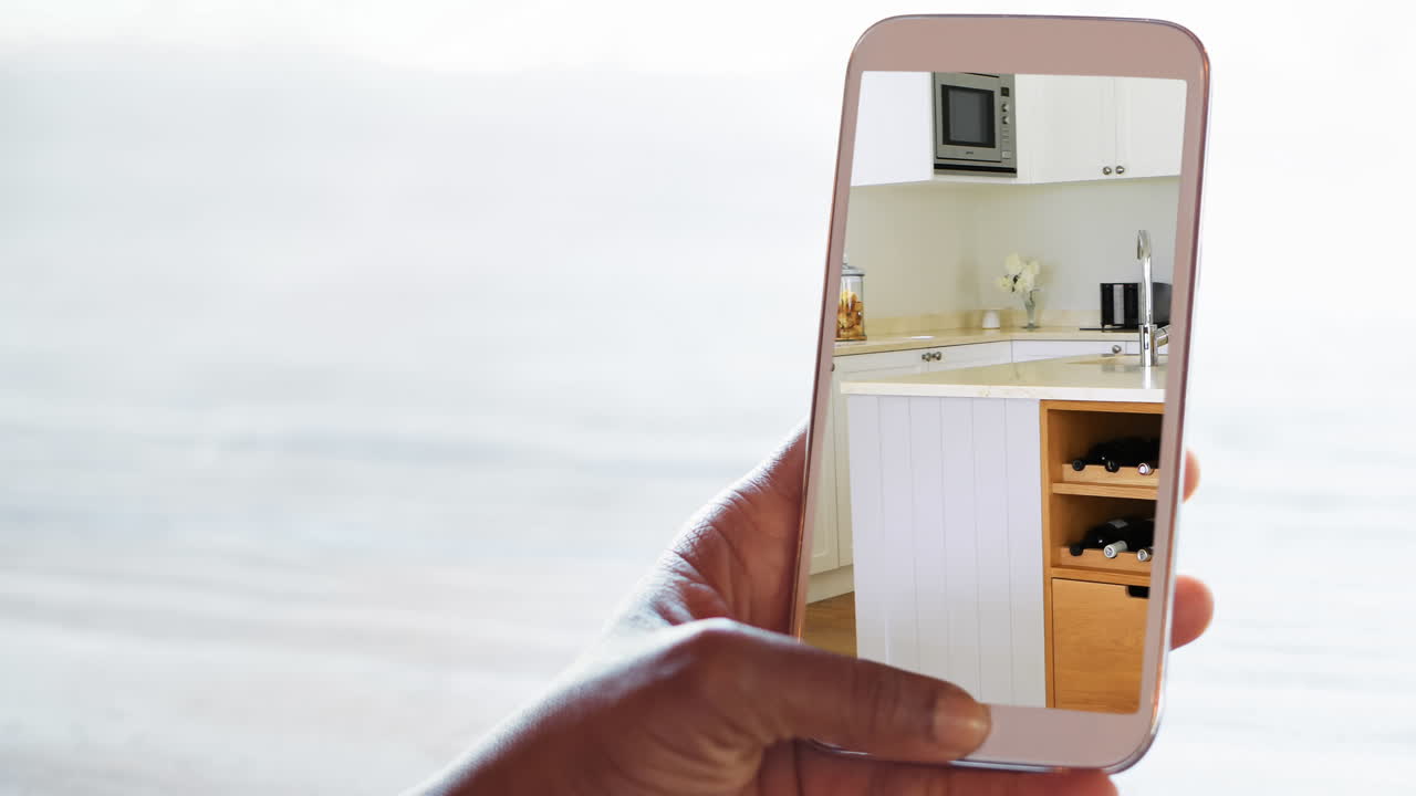 Person holding smartphone with modern kitchen interiors displayed on screen